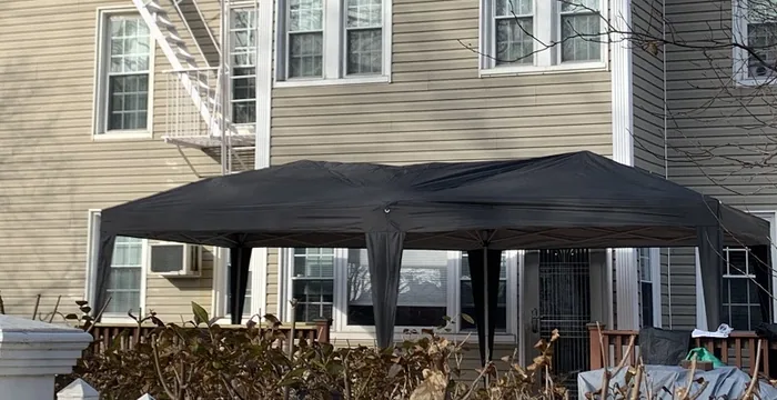 Black canopy tent set up beside a house