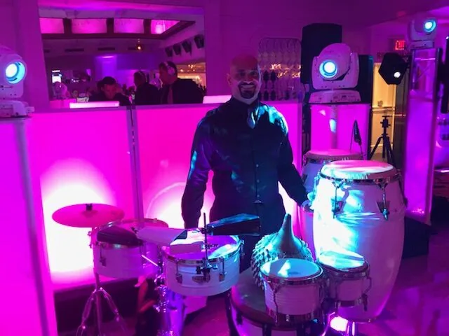 DJ playing congas under pink uplighting