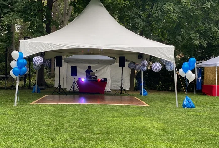 Tent with balloons and a DJ set up on a lawn